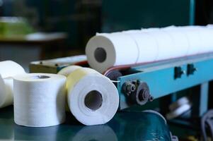 Toilette Papier Rollen ziehen um entlang das Förderer Gürtel. alt griechisch Fabrik zum das Produktion von Papier Rollen zum Hygiene. Herstellung von Papier Handtücher und Toilette Papier. schließen oben Sicht. selektiv Fokus foto