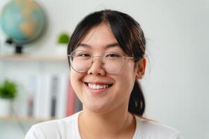 ein Porträt von jung asiatisch Frau tragen Brille, lächelnd und suchen beim das Kamera foto