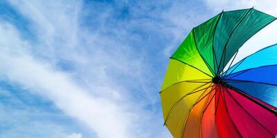 bunt Regenbogen Regenschirm auf Blau Himmel Hintergrund. LGBT, Stolz Monat, Diversität, Sonnenschutz Konzept. foto