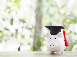 Schweinchen Bank mit Abschluss Hut. das Konzept von Speichern Geld zum Ausbildung, Schüler Darlehen, Stipendium, Unterricht Gebühren im Zukunft foto