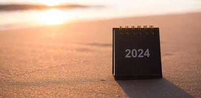 schließen oben 2024 Schreibtisch Kalender auf das Strand im das Sonnenuntergang Zeit. Auflösung, Ziel, Aktion, Planung, und verwalten zu Erfolg Geschäft. foto