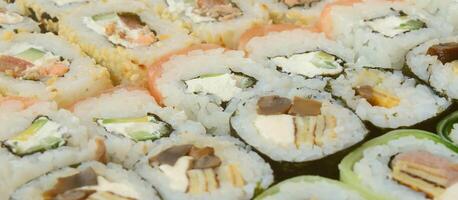 Nahaufnahme vieler Sushi-Rollen mit verschiedenen Füllungen. Makroaufnahme gekochter klassischer japanischer Speisen. Hintergrundbild foto