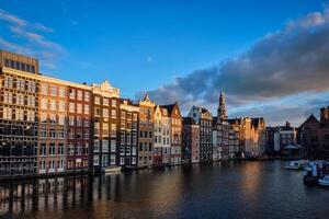 Häuser und Tourist Boote auf Amsterdam Kanal Seebrücke damrak auf Sonnen foto