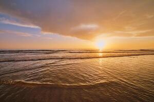 atlantisch Ozean Sonnenuntergang mit wogend Wellen beim fonte da telha Strand, Portugal foto