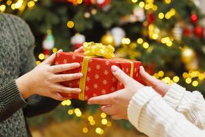 Hände von Elternteil geben Weihnachten Geschenk zu Kind auf Weihnachten Baum Hintergrund foto