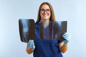 Frau Arzt Analysen Röntgen Bilder von Patienten verletzt Bein auf ein Blau Hintergrund foto