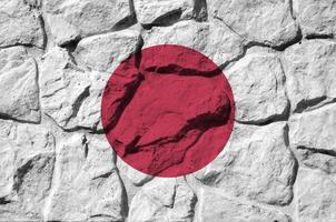 Japan Flagge abgebildet im Farbe Farben auf alt Stein Mauer Nahaufnahme. texturiert Banner auf Felsen Mauer Hintergrund foto