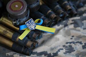 ukrainisch Symbol auf Maschine Gewehr Gürtel Lügen auf ukrainisch pixelig Militär- tarnen foto