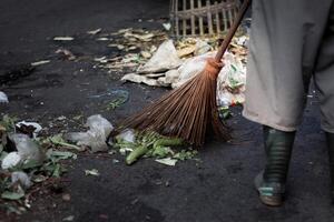 Mann mit Besen fegen Straße oder Fußboden Stadt Müll Reinigung Bedienung Konzept. Instandhaltung Arbeiter Reinigung das Straße mit ein Besen. Kopieren Raum foto