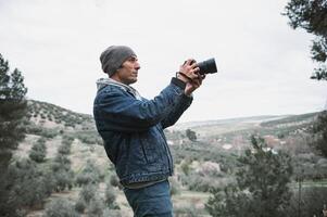 jung Reisender Fotograf Mann mit ein Kamera, nehmen Bilder von Berge während Trekking im das früh Frühling Natur foto