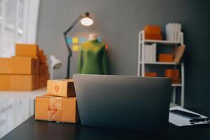 Startup-Kleinunternehmer oder freiberufliche Asiatin, die einen Laptop mit Box verwendet, junge Erfolgsasiatin mit erhobener Hand, Online-Marketing-Verpackungsbox und Lieferung, KMU-Konzept. foto