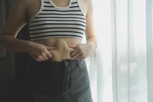 Frauen Körper Fett Bauch. fettleibig Frau Hand halten übermäßig Bauch fett. Diät Lebensstil Konzept zu reduzieren Bauch und gestalten oben gesund Bauch Muskel. foto