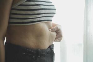 Frauen Körper Fett Bauch. fettleibig Frau Hand halten übermäßig Bauch fett. Diät Lebensstil Konzept zu reduzieren Bauch und gestalten oben gesund Bauch Muskel. foto