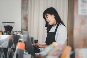 schön Frau Barista vorbereiten Tasse von Kaffee zum Kunde im Kaffee Geschäft. foto