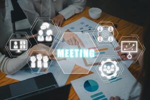 Treffen Konzept, Geschäft Mannschaft Analysieren Einkommen Diagramme und Grafiken auf Büro Schreibtisch mit Treffen Symbol auf virtuell Bildschirm. foto