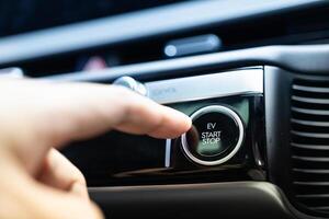 Treiber schieben ein Fahrzeug Motor Start Taste. drücken das elektrisch Auto Motor Start halt Taste. foto