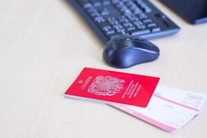 Nahansicht von Reisepass und Flugzeug Tickets platziert auf das Schreibtisch in der Nähe von das Computer. bereiten zum Reise. Urlaub Konzept foto