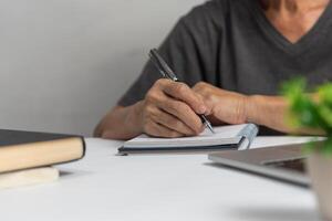 Frau Hände mit Stift Schreiben auf Notizbuch im das office.learning, Bildung und Arbeit.schreibt Ziele, Pläne, machen zu tun und Wunsch aufführen auf Schreibtisch. foto