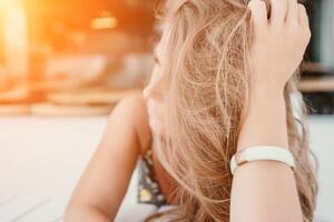 glücklich Frau Porträt im Cafe. Boho schick Mode Stil. draussen Foto von jung glücklich Frau mit lange Haar, sonnig Wetter draußen Sitzung im modern Cafe.