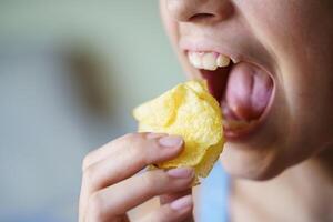 Ernte jung Mädchen mit Mund breit öffnen Über zu Essen Kartoffel Chips foto