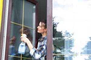 Frau manuell wäscht das Fenster von das Haus mit ein Lappen mit sprühen Reiniger und Mopp Innerhalb das Innere mit Weiß Vorhänge. Wiederherstellen bestellen und Sauberkeit im das Frühling, Reinigung warten foto