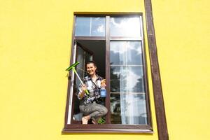 ein Frau manuell wäscht das Fenster von das Haus mit ein Lappen mit ein sprühen Reiniger und ein Mopp außen. Sicherheit beim Höhe, Wiederherstellen bestellen und Sauberkeit im das Frühling, Reinigung Bedienung foto