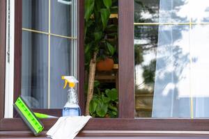 ein Fenster Reinigung sprühen, ein Lappen und ein Mopp Stand auf das Fenster Schwelle von ein öffnen Fenster draußen zum Frühling Allgemeines Reinigung foto