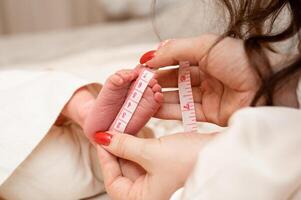 Mutter Maße das Größe von ein Neugeborene Babys Füße, Nahansicht foto