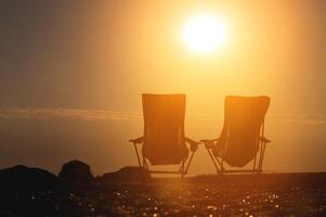 zwei falten Camping Stühle gegen das Hintergrund von das Rahmen Sonne. Camping Tourismus. niemand foto