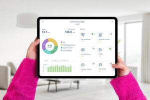 Hände halt Tablette im Leben Zimmer mit Elektrizität Verwendungszweck Anwendung, Überwachung Verbrauch und steuern Zuhause Geräte. Konzept von Clever Energie Verwaltung foto
