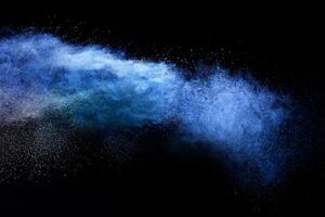 abstrakt braun Pulver Explosion, Nahansicht von Blau Staub Partikel Spritzen auf schwarz Hintergrund foto