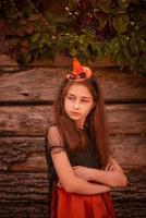 ein Mädchen in einem Kürbiskostüm auf einem hölzernen Hintergrund im Herbst. Halloween und Kinder. foto