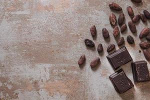 Schokoladenstücke mit rustikalem Hintergrund der rohen Kakaobohnen. hochwertiges schönes Fotokonzept
