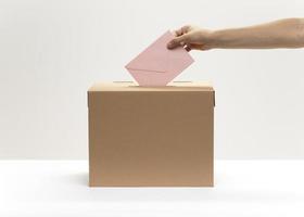 Hand legt rosa Umschlag in Abstimmungsbox. hochwertiges schönes Fotokonzept foto