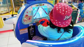 Semarang, Indonesien - - Februar, 2024 - - ein Mädchen Fahrten ein Flugzeug Spiel auf das Spielplatz foto