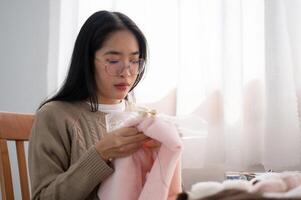 ein jung asiatisch Frau ist Fokussierung auf Einfädeln ein Muster auf ein Stickerei rahmen, Hand Nähen auf Tuch. foto