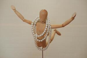 hölzern Mannequin mit Perlen auf ein hölzern Hintergrund. foto