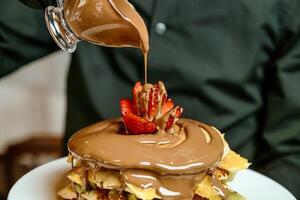 Person Gießen Schokolade Soße auf ein dekadent Dessert foto