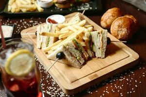 hölzern Schneiden Tafel mit Hälfte Sandwich und Französisch Fritten foto