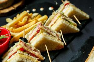 Teller von Sandwiches und Französisch Fritten auf schwarz Teller foto