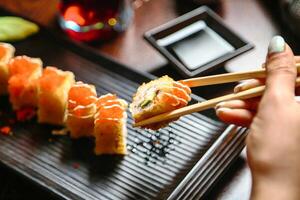 Person genießen Sushi mit Essstäbchen foto