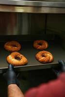 Person im rot Hemd Putten Donuts im Ofen foto