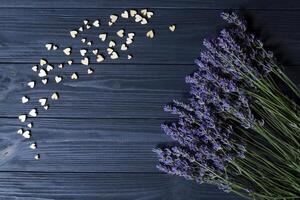 Lavendel Blumen und hölzern Liebe Herzen auf ein dunkel Blau hölzern Tisch. schön romantisch Hintergrund mit Kopieren Raum. foto