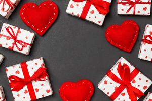 Draufsicht auf festliche Geschenkboxen und rote Textilherzen auf buntem Hintergrund mit Kopierraum. Valentinstag-Konzept foto