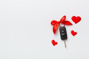 Auto Schlüssel mit ein rot Bogen und ein Herz auf farbig Tisch. geben Geschenk oder Geschenk zum Valentinstag Tag oder Weihnachten, oben Aussicht mit Kopieren Raum foto