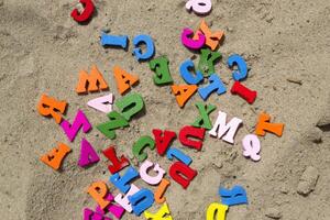 Mehrfarbig hölzern Briefe auf ein Sand schließen hoch. foto