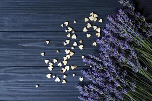 Lavendel Blumen und hölzern Liebe Herzen auf ein dunkel Blau hölzern Tisch. schön romantisch Hintergrund mit Kopieren Raum. foto