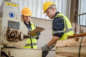 Arbeiter Tischler Arbeiten im Maschinen zu Schnitt Holz Holz. Mann und Frau sind basteln mit Holz im ein Werkstatt. zwei Handwerker oder Handwerker Arbeiten mit Zimmermann Werkzeuge oder elektrisch Maschinen. foto