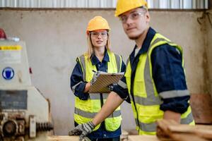 Arbeiter Tischler Arbeiten im Maschinen zu Schnitt Holz Holz. Mann und Frau sind basteln mit Holz im ein Werkstatt. zwei Handwerker oder Handwerker Arbeiten mit Zimmermann Werkzeuge oder elektrisch Maschinen. foto