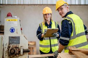 Arbeiter Tischler Arbeiten im Maschinen zu Schnitt Holz Holz. Mann und Frau sind basteln mit Holz im ein Werkstatt. zwei Handwerker oder Handwerker Arbeiten mit Zimmermann Werkzeuge oder elektrisch Maschinen. foto